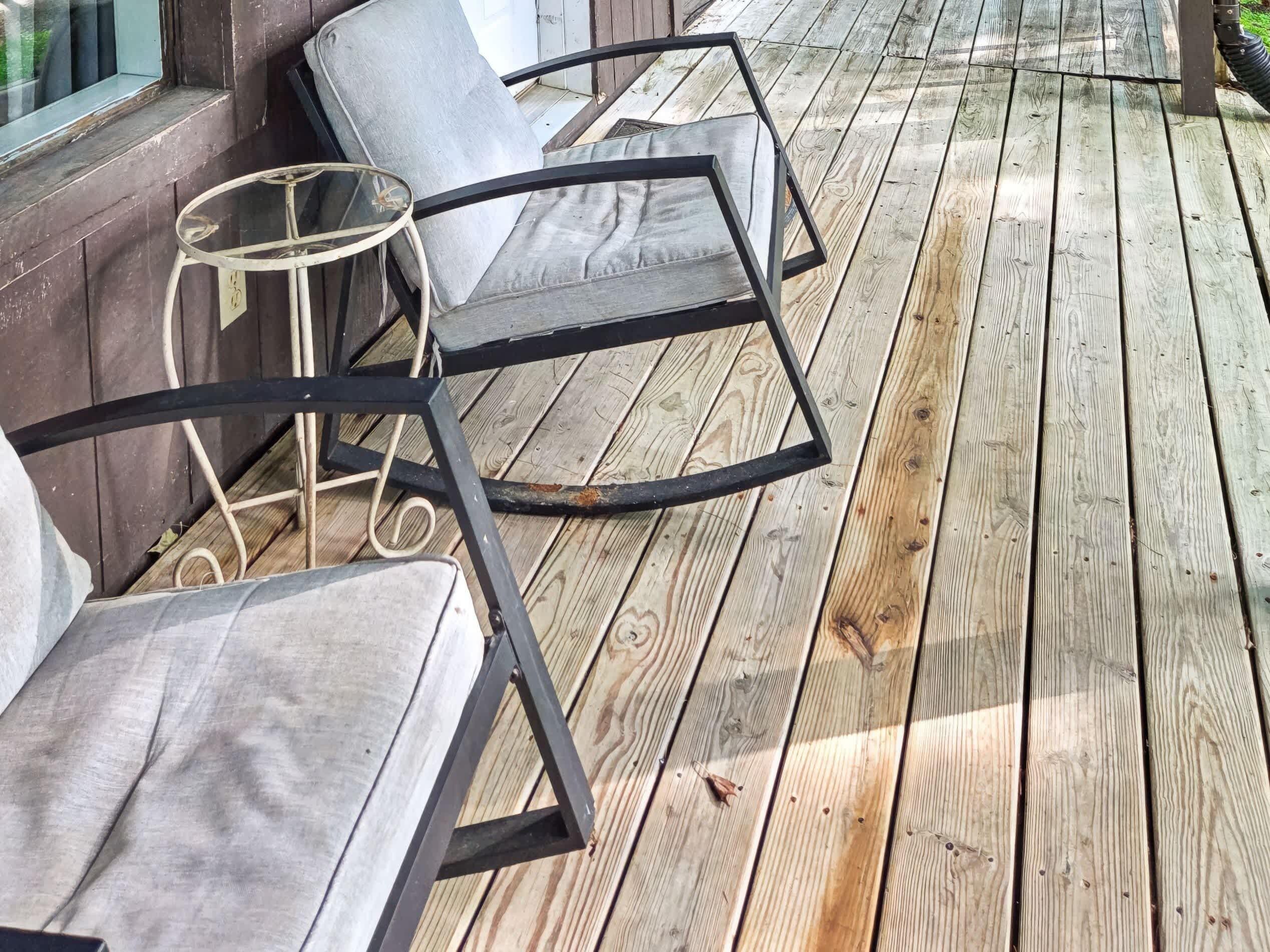 A wooden deck with outdoor furniture, including chairs and a table.