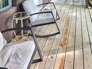 Una terraza de madera con muebles de exterior, incluyendo sillas y una mesa.