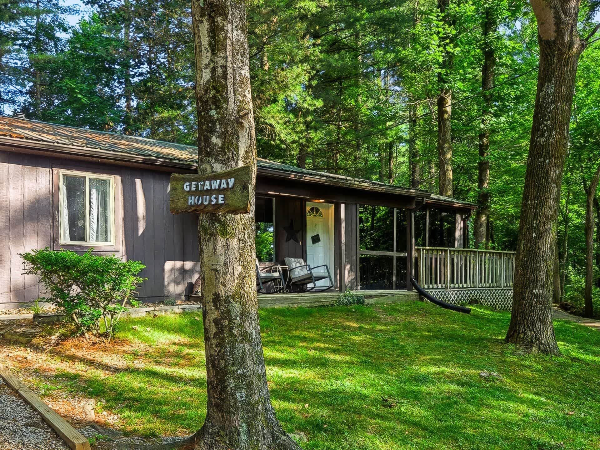 Eine Hütte mit dem Schild 'GETAWAY HOUSE', einem Balkon, Sitzgelegenheiten im Freien und einer Hängematte.