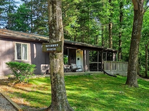 A cabin labeled 'GETAWAY HOUSE' with a porch, outdoor seating, and a hammock.