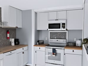 A kitchen with white cabinets, a microwave, a toaster, and a coffee maker.
