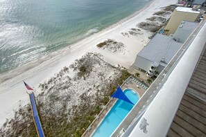A beachside hotel with a swimming pool, a flag, and a view of the ocean. - Beautiful Beachfront 3 Bedroom Condo (Gulf Shores)