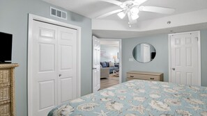 A bedroom with a bed, dresser, and a ceiling fan.