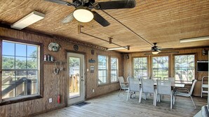 Ein geräumiges Zimmer mit Holzwänden, großen Fenstern und einem Deckenventilator.