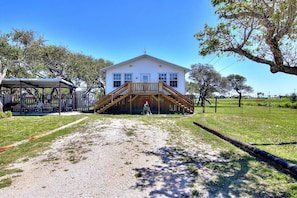 A two-story house with a covered porch and a staircase leading to the entrance.