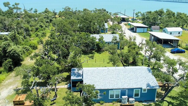 Une propriété située sur la côte, comprenant plusieurs bâtiments, un quai et un pont en arrière-plan.