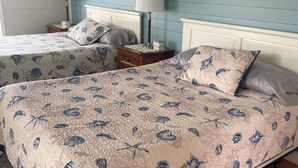 A bedroom with two beds, a nightstand with lamps, and a wall with fish decorations.