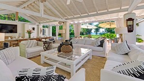 A spacious living area with white furniture, a ceiling fan, and a TV. - Landmark House & Cottage  Summer Promotion | Beach Front - Located in  Exquisite Saint James with Private Chef Services (Saint James)