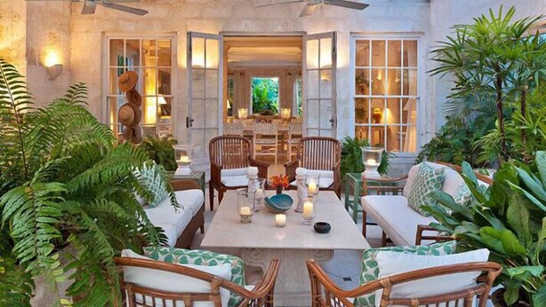 An outdoor dining area with wicker furniture and a table set for two, surrounded by lush greenery. - Leamington House  Summer Promotion | Near Ocean - Located in  Wonderful St. Peter with Private Pool (Little Battaleys)