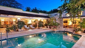 A pool area with a curved design, surrounded by potted plants and outdoor seating. - Leamington House  Summer Promotion | Near Ocean - Located in  Wonderful St. Peter with Private Pool (Little Battaleys)