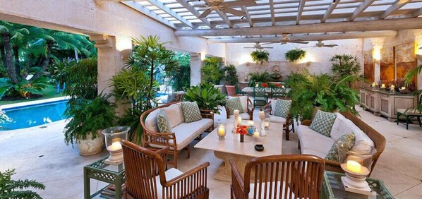 Une terrasse extérieure avec des sièges, une piscine et une végétation luxuriante.