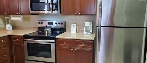 A kitchen with stainless steel appliances, wooden cabinets, and a countertop.