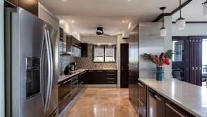 Una cocina moderna con electrodomésticos de acero inoxidable, encimera de mármol y ventilador de techo.