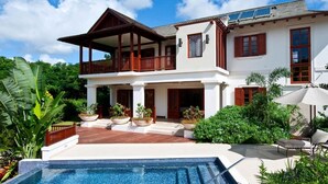 A two-story house with a balcony, a swimming pool, and outdoor furniture. - Villa Alila  | Near Ocean - Located in  Exquisite Sandy Lane with Private Pool (Holetown)