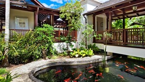 A koi pond surrounded by lush greenery and wooden walkways. - Villa Alila  | Near Ocean - Located in  Exquisite Sandy Lane with Private Pool (Holetown)
