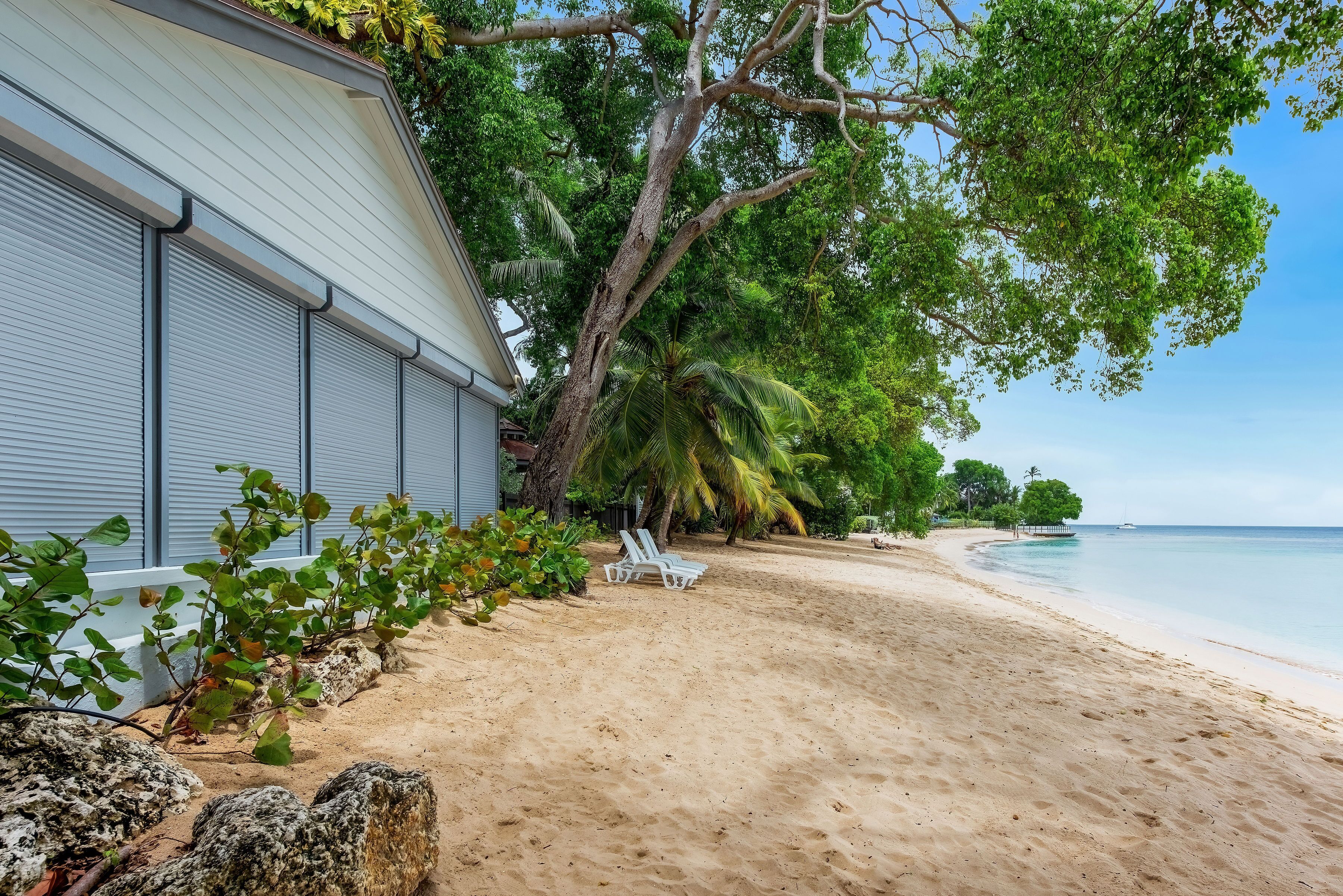 A beach with a building, palm trees, and a clear sky.