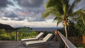 Une terrasse avec des chaises longues et vue sur l’océan.