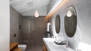 Une salle de bain moderne équipée d’une douche, de toilettes, d’un meuble-lavabo et de deux miroirs fixés au mur.