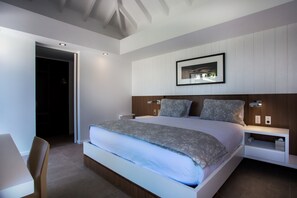 A modern bedroom with a large bed, bedside tables, and a framed picture on the wall. - Villa Angelique  | Ocean View - Located in  Wonderful Saint Jean with Private Pool (Saint Barthélemy)