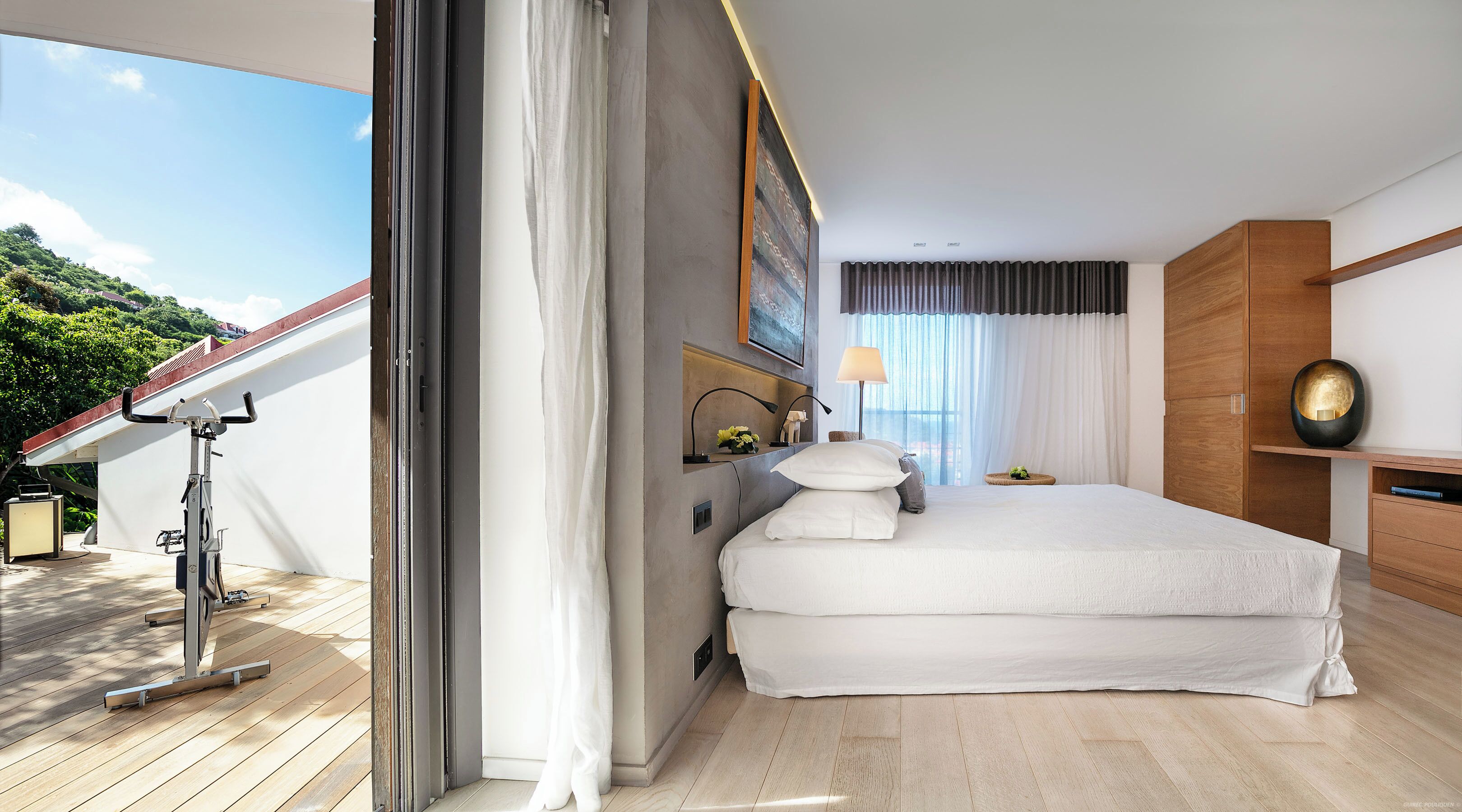 A modern hotel room with a large bed, a desk, a chair, and a view of the outdoors.