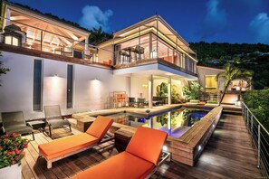 A modern house with a swimming pool, outdoor seating, and a balcony.