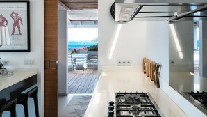 A modern kitchen with a central island, a gas stove, and a view to an outdoor terrace.