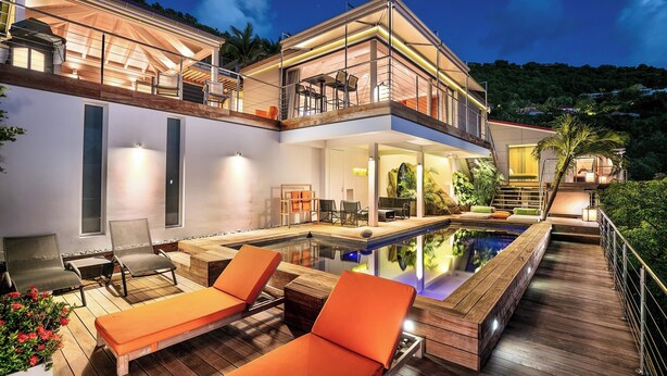 A modern house with a swimming pool, outdoor seating, and a balcony.