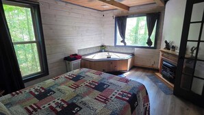 Interno di una cabina con un letto, una finestra, una ventola a soffitto e un piccolo bagno.