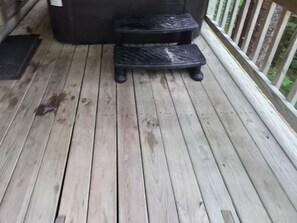 Une terrasse en bois avec un jacuzzi et deux marches.