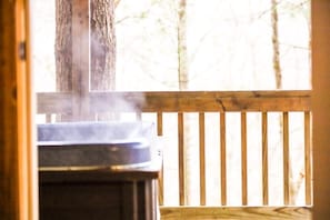 A wooden deck with a hot tub, a tree trunk, and a railing. - Eagles Nest at Avenwood Cabins (new straitsville)