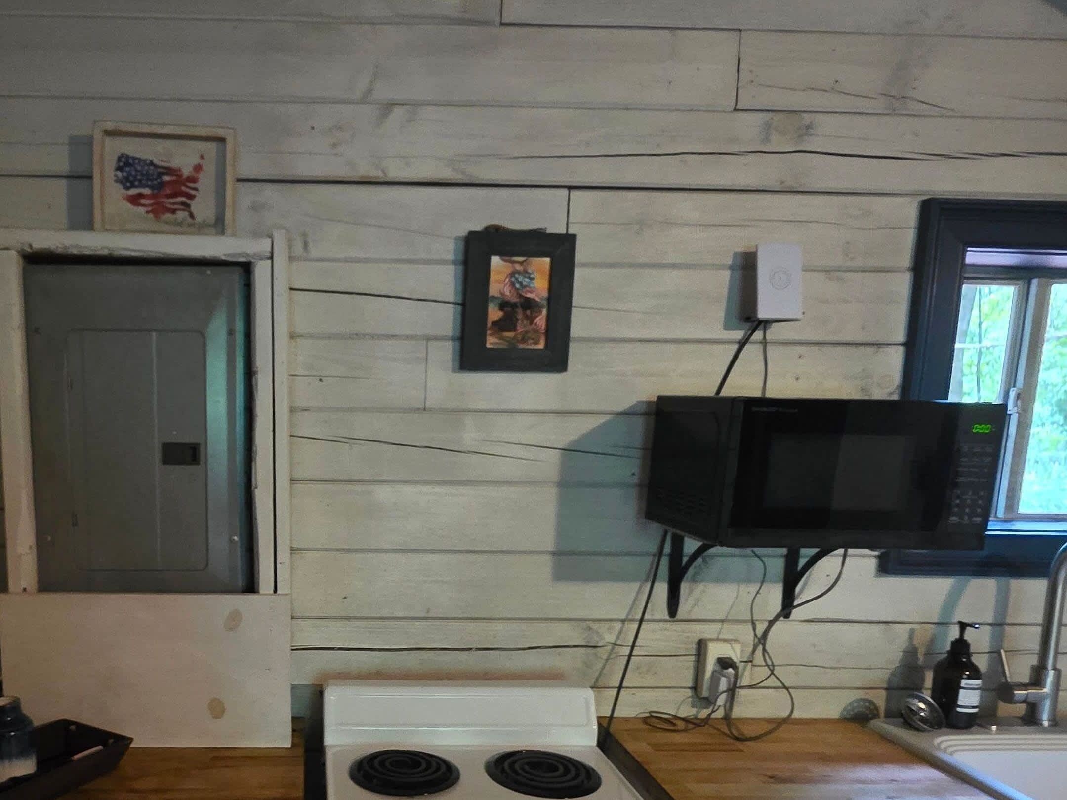 A kitchen with a microwave, stove, and a framed picture on the wall.