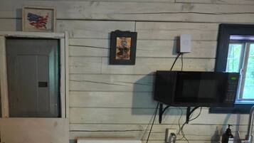 A kitchen with a microwave, stove, and a framed picture on the wall.