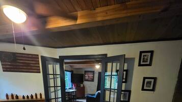 Una stanza con soffitto in legno, un camino, un'area pranzo e una vista da una porta.