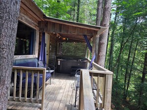 Une cabane en bois dotée d’une terrasse, d’un bain à remous et d’un espace salon abrité.