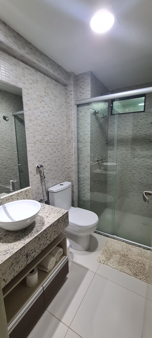 A modern bathroom with a glass-enclosed shower, a white sink, and a toilet.
