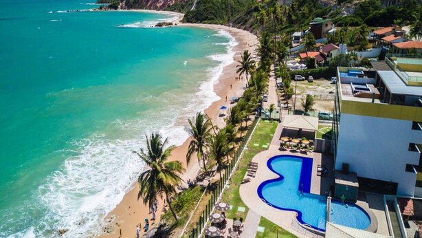 Un resort con playa, piscina y vistas al océano.