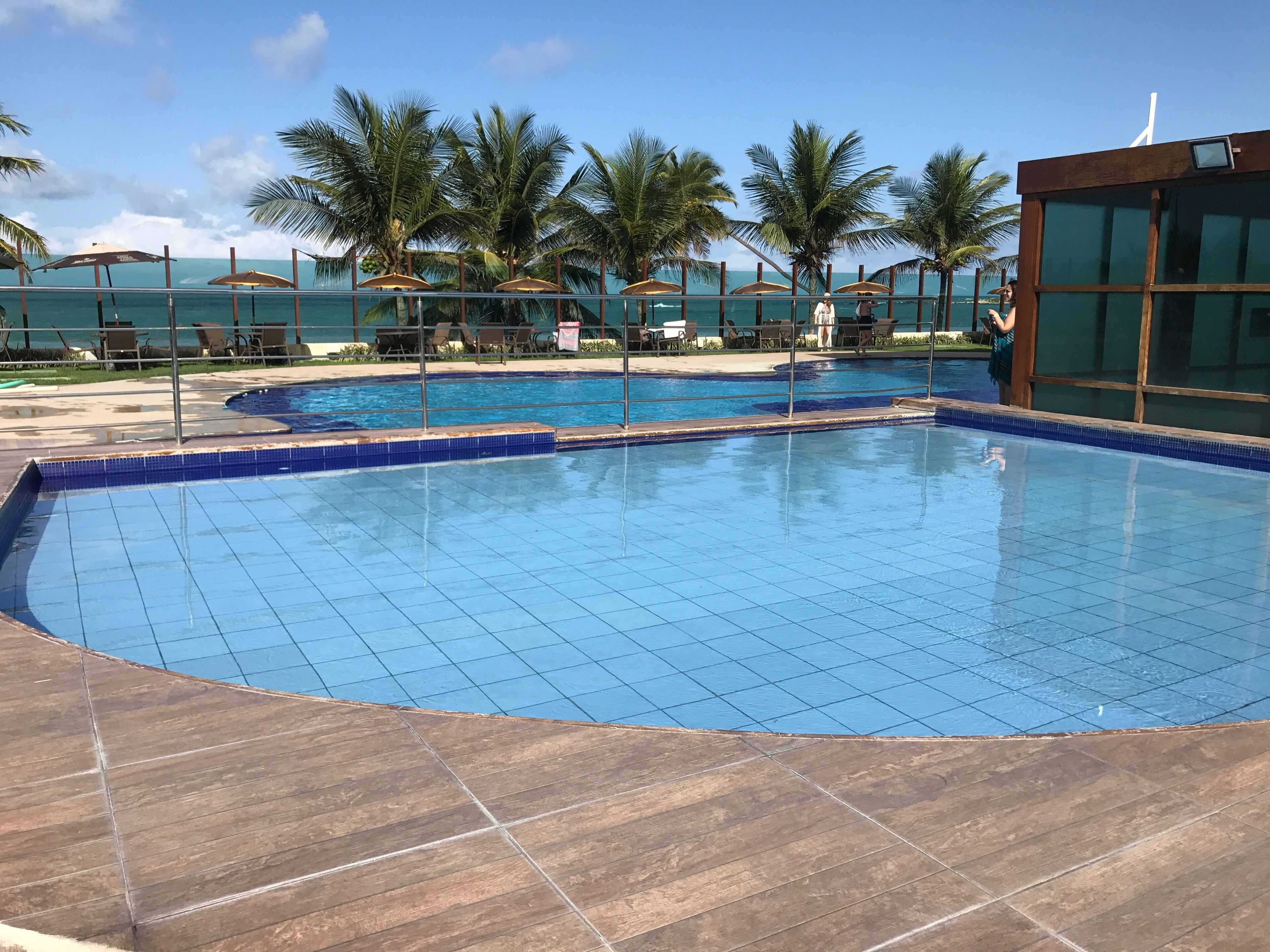 Ein Swimmingpool mit gefliestem Boden und Palmen im Hintergrund.