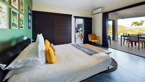 Een moderne slaapkamer met een groot bed, een schuifdeur naar een balkon en kunstwerken aan de muren.