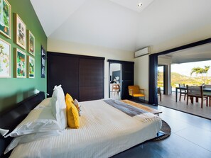 A modern bedroom with a large bed, a sliding door to a balcony, and artwork on the walls.