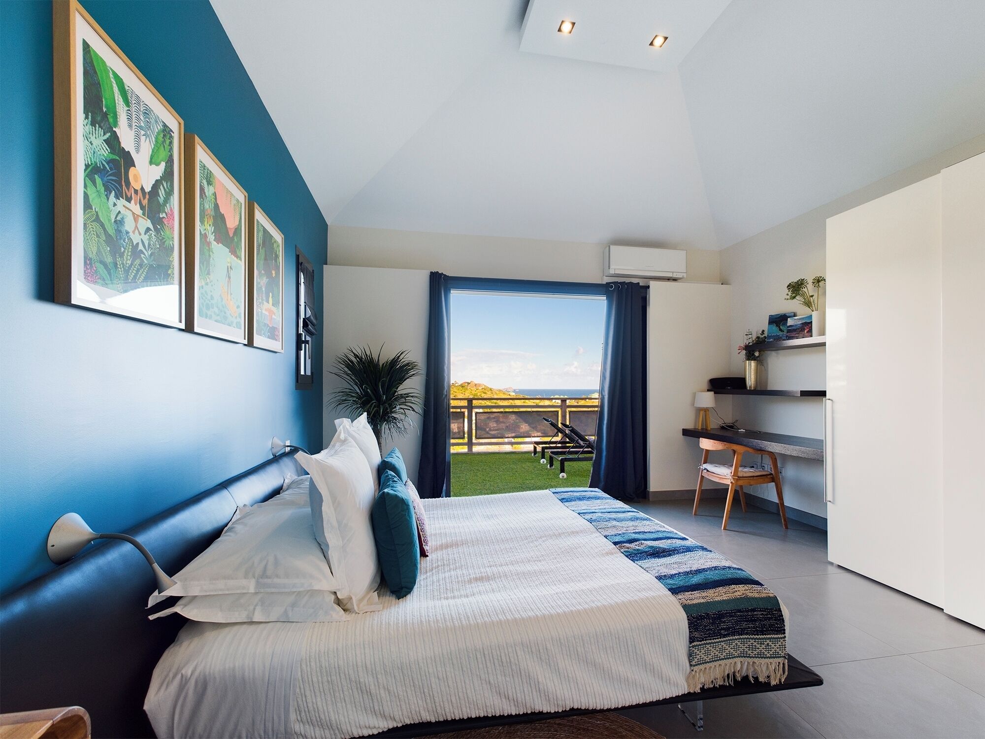 Een slaapkamer met een bed, een bureau en uitzicht op een groen landschap.