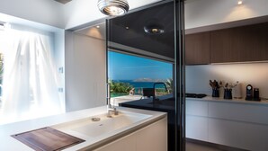 Eine moderne Küche mit großem Fenster, einer integrierten Spüle und Meerblick.
