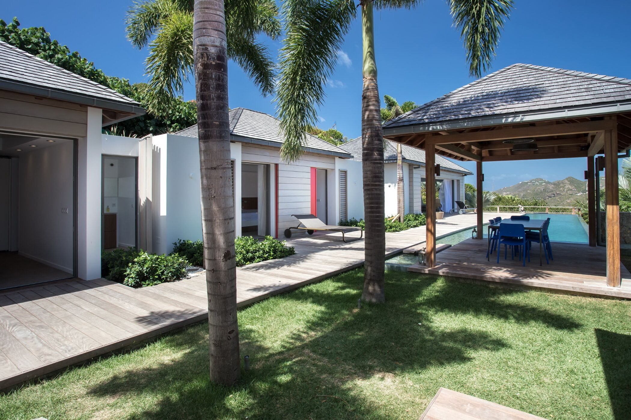 A modern house with a covered outdoor area, a pool, and a view of mountains.