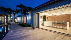 Une maison moderne dotée d’une piscine, d’un coin bar et d’une terrasse bien éclairée.