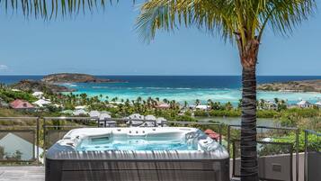 Relax in the hot tub surrounded by a tropical beach and ocean views.