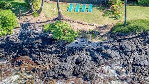 A resort with a pool, lounge chairs, and palm trees. - Oceanfront Luxury at Alii Point | Private Pool, Panoramic Views & Tropical Serenity (Kailua-Kona)