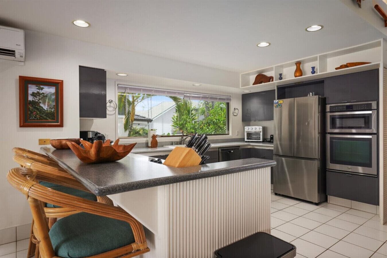 Uma cozinha moderna com uma ilha central, eletrodomésticos de aço inoxidável e vista para o verde lá fora.