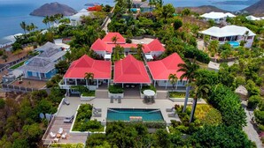 Ein Resort mit mehreren Gebäuden mit roten Dächern, einem Schwimmbad und üppiger Bepflanzung.