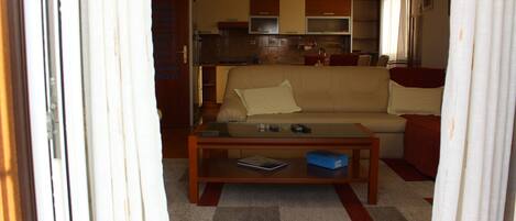 A living room with a sofa, coffee table, and a kitchen in the background.