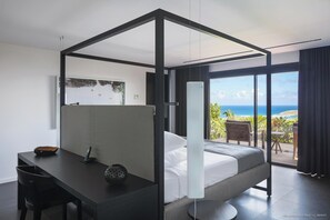 Een moderne slaapkamer met een hemelbed, een bureau met stoel en uitzicht op de oceaan.