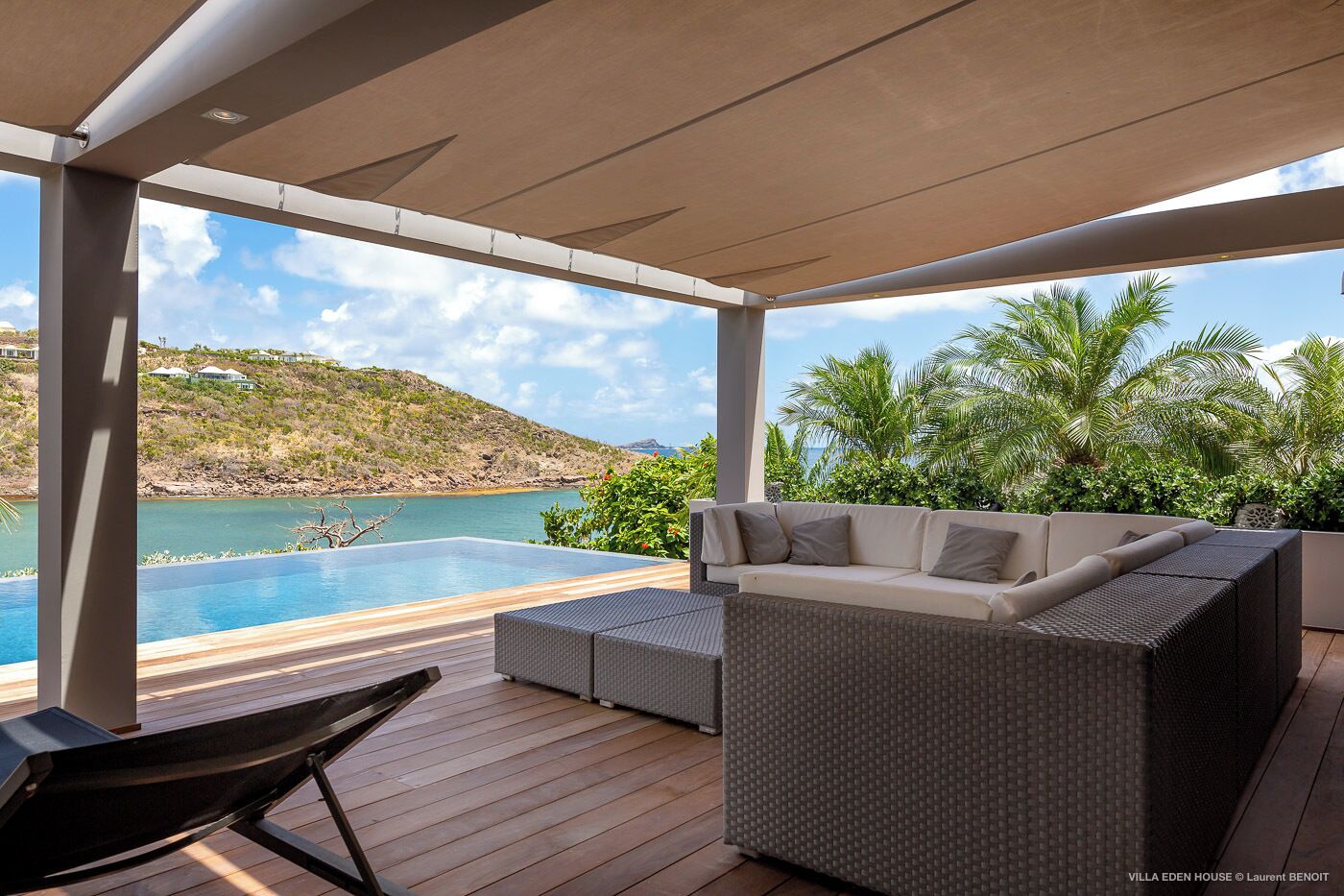 Un espace extérieur abrité, doté d’une piscine, de meubles en osier et offrant une vue sur la mer et les collines.